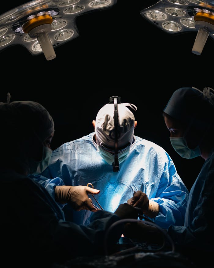 Surgeons focused in an operating room performing lifesaving surgery under bright surgical lights.